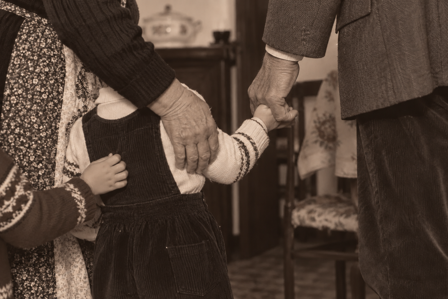 Un bambino tiene le mani di due adulti all’interno di una casa.