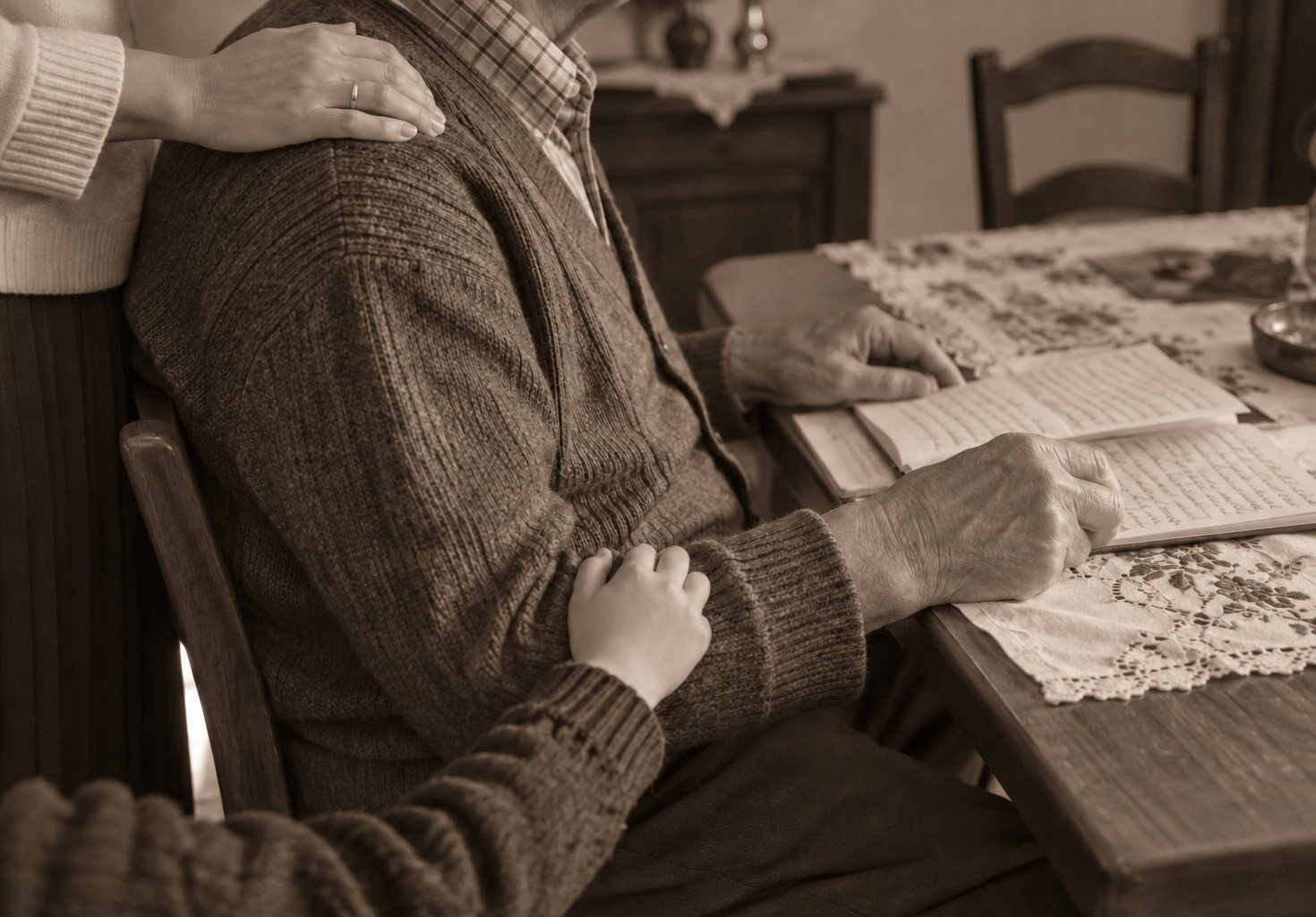 Un uomo anziano scrive su un quaderno mentre i familiari gli posano le mani sulla spalla e sul braccio.